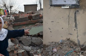 Frau zeigt auf ihr zerstörtes Haus
